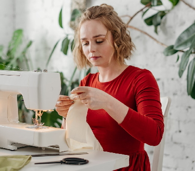 Person sitting at a sewing machine with good sewing posture, working with fabric in a bright, well‑lit workspace.
