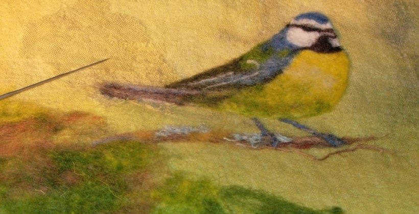 Needle-felt picture of a blue tit sitting on a branch.