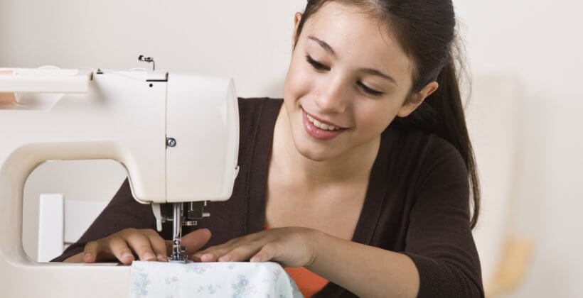 Kids learn to sew class - a young girl enjoying using her sewing machine