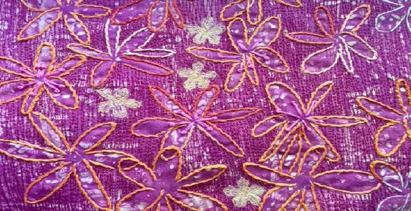 Monoprinted fabric with large daisy-like flowers which have been machine and hand embroidered