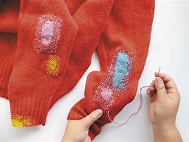 Repair your clothes - image of a red sweater with holes mending by colourful patches and stitching