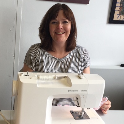 Sewing for mental Health. A smiling woman sitting at her sewing machine