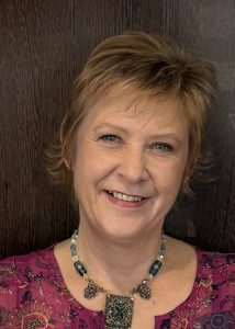 Photo of Artisan Stitch Founder, Jen Skedd at the Scotland Prestige Awards, October 2025. Jen is smiling and standing against a wooden-panelled wall. 