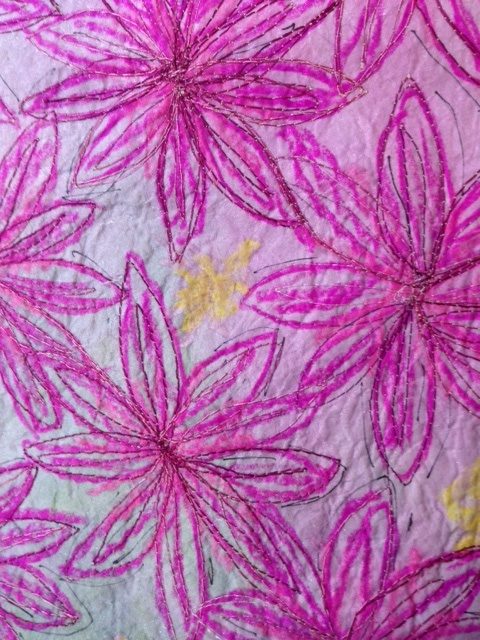 Expressive textile artwork reflecting my creative textiles journey. It features large stitched flowers in purples and pinks on a soft blue‑green background